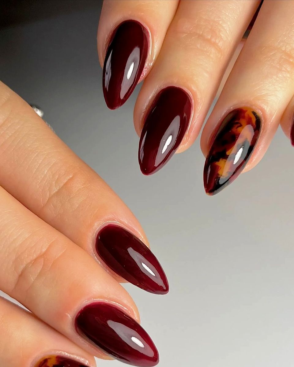 Deep cherry red almond nails with a tortoiseshell accent nail by The Nail Editor